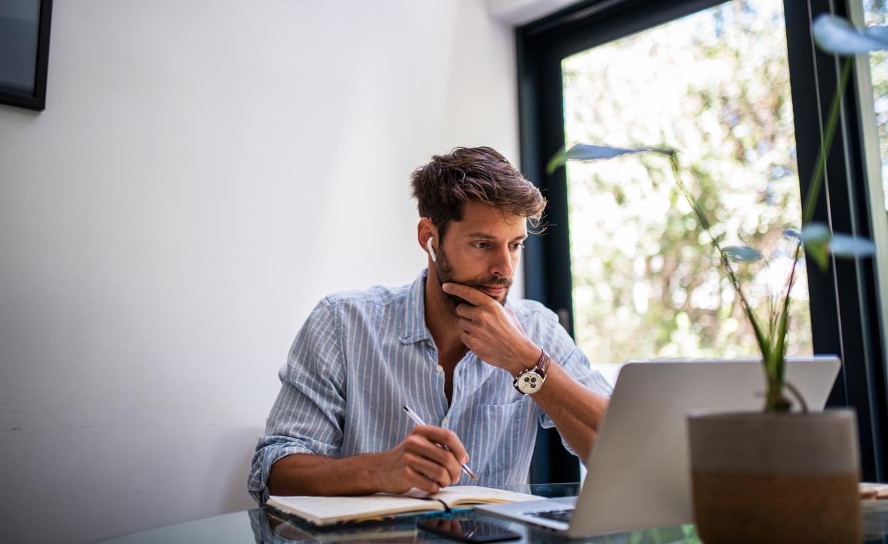 A photo shows a man looking thoughtfully at a computer.