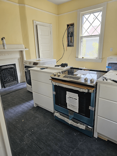 Kitchen under renovation with appliances and old-fashioned fireplace.