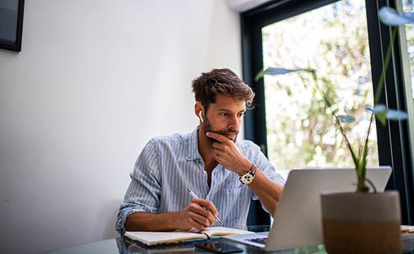 An image shows a focused man looking at a laptop screen
