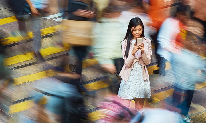 Woman in the middle of a blurry crowd, looking at her device